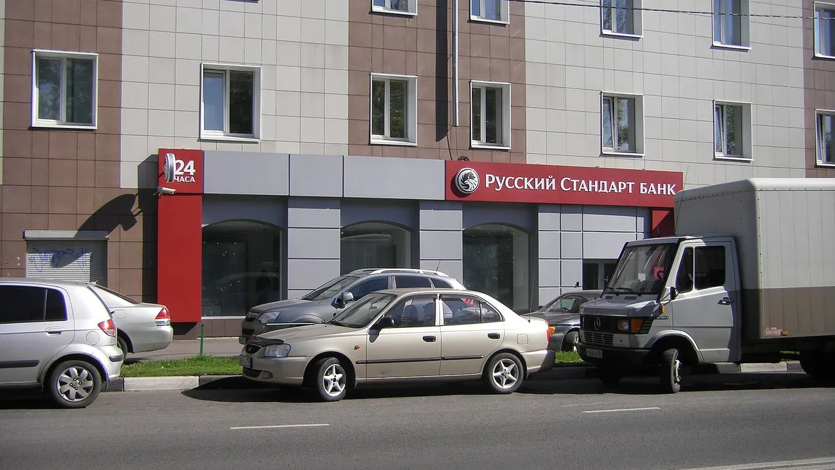 Отделение Банка Русский Стандарт на первом этаже жилого дома, у входа припаркованы машины